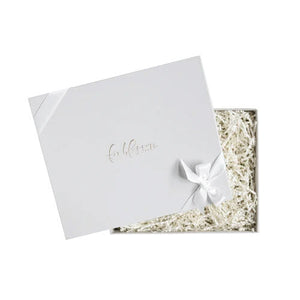 Light grey box with foxblossom.co embossed with gold foil, filled with white paper shred and  tied with white ribbon. 