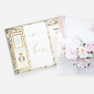 Cape cod gifting box with ivory paper shred. Gold and white The Gem Pen box, white vow books with gold embossed script, Mast tea chocolate, Wedding magazine with bouquet