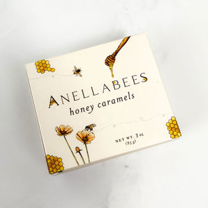 Cream/yellowish toned box. drawings of honey combs, bees, flowers, and honey stir on front. "Annellabees, honey caramels" (brand/product) and serving amount on front. 