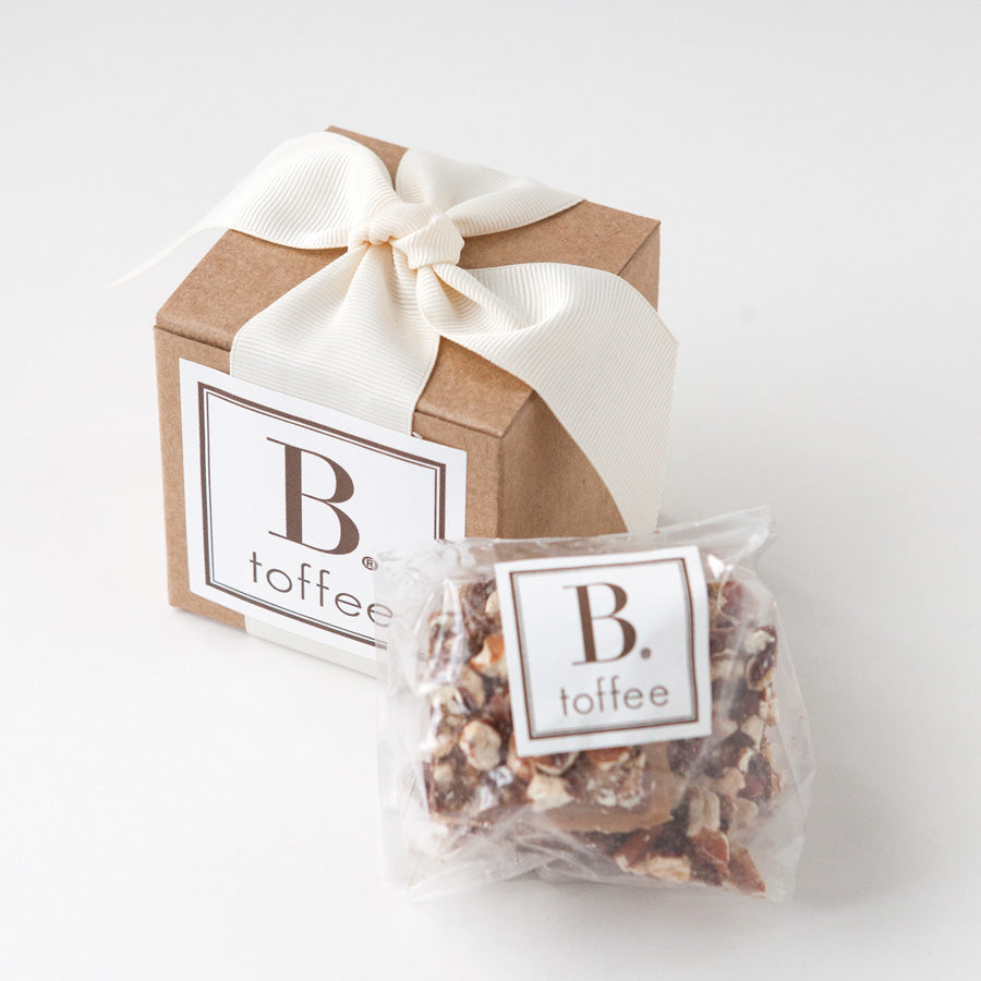 Gold clip coffee spoon, 'b toffee' with an ivory ribbon, Mocha morning granola in a cylinder can, 'canyon' coffee in a brown paper bag, and two black ceramic mugs, in ivory paper shread, in a gray 'foxblossm' box,