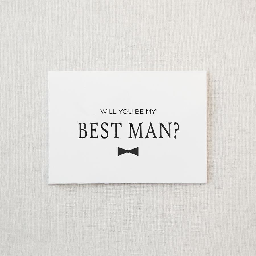 White envelope size card (approx. 3.5" x 5"), reads, "Will you be my best man?" in black text with a black bowtie graphic.