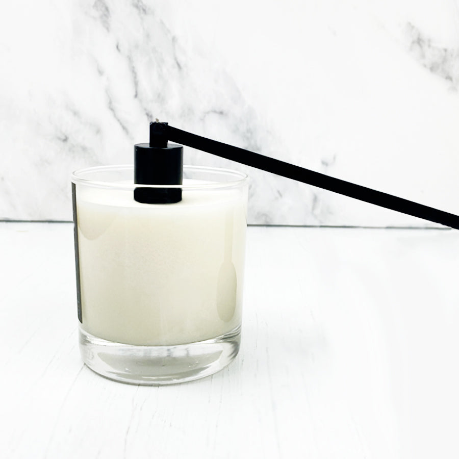 Black candle snuffer featured snuffing a white candle in a clear jar on a background.