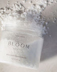Image of the bloom wild rose and sandalwood bath soak opened showing it's transparent jar and white salts. 