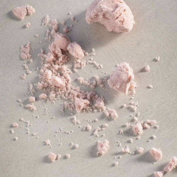 White and pink colored cylinder container, black text, inside bath truffle a cream frozen yogurt like texture.