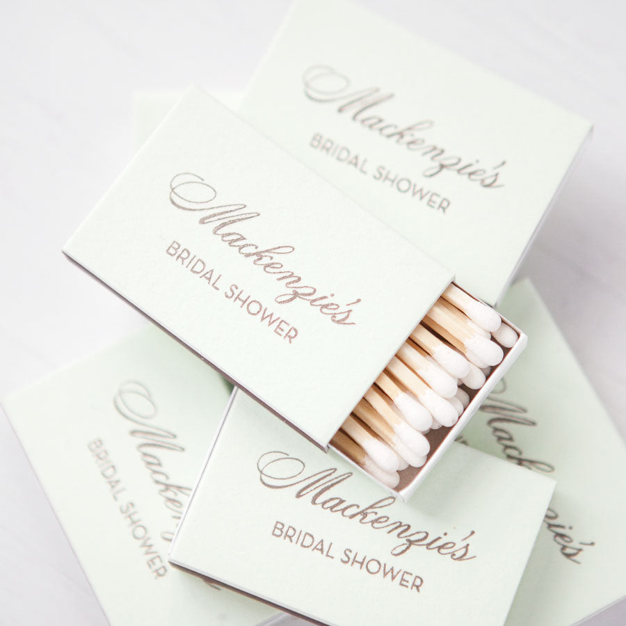 Green tea colored 2.22" x 1.375" x .46" personalized matchboxes with gold script with Mackenzie's Bridal shower. Approx. 22 white matches in each.
