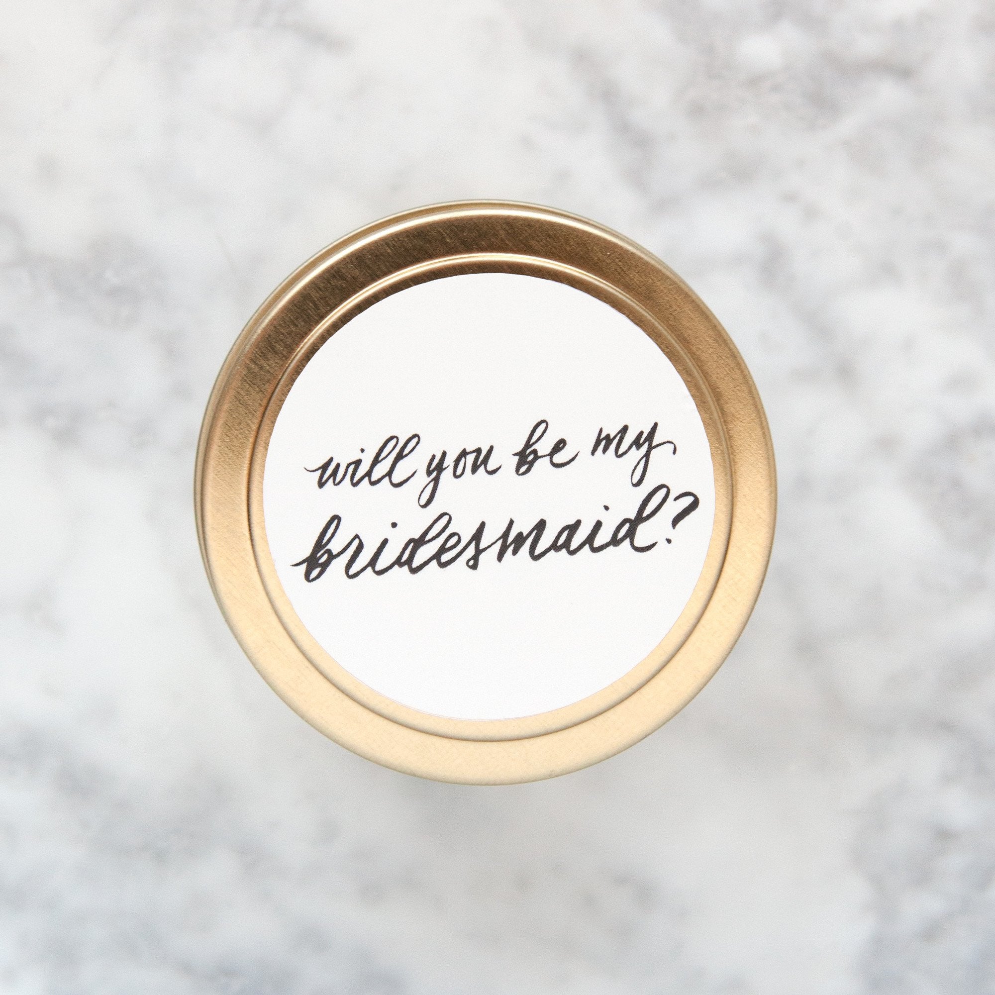4 oz gold candle tin. Reads "will you be my bridesmaid?" in gold script