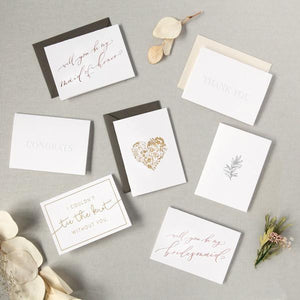 Seven car options, and floral bundles/flower stems. some read, "will you be my maid of honor?", "Congrats", "I couldn't tie the knot without you", "thank you", and will you be my bridesmaid?". Others have a golden heart and floral graphics. A few paired with envelope color options: slate gray or ivory shimmer.