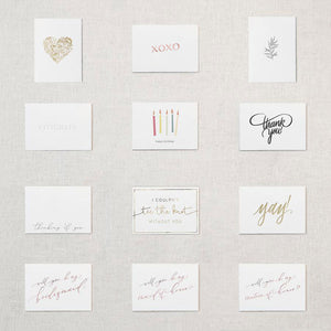 Display of twelve white cards. Gold floral heart, pink “xoxo”, gray botanical branch, “congrats” embossed, “happy birthday” under five multicolored candles, “thank you!” in gray script, “thinking of you” in grey script, “I couldn't tie the knot without you” gold foil, “Yay!” in gold foil, “will you be my bridesmaid” rose gold,” will you be my maid of honor’ rose gold, “will you be my matron of honor” rose gold