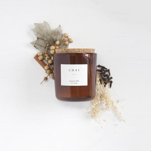 8 oz chai scented soy candle, approx 3.25" x 3.75", brown glass container with cork lid and white sticker. Pictured with dried autumn themed florals