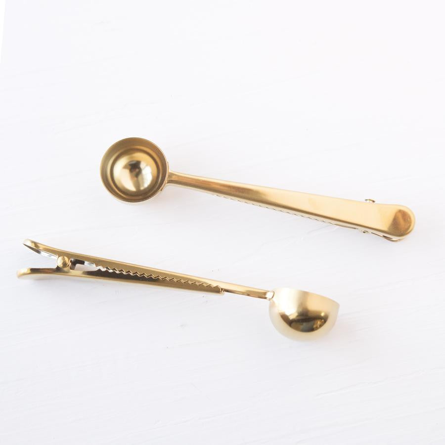 Stainless steel gold coffee scoop two of them in different positions.