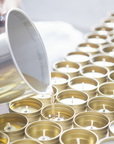 Our candles being poured and in the making in their gold tins and clear wax.