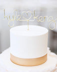 Custom Wire Cake Topper in gold aluminum wire personalized with Kyle Heart shape Kenz on top of a cake. 