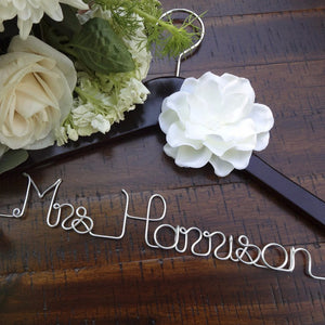 Dark wooden hanger with ivory flower and silver hook. Personalized base wire shaped into name