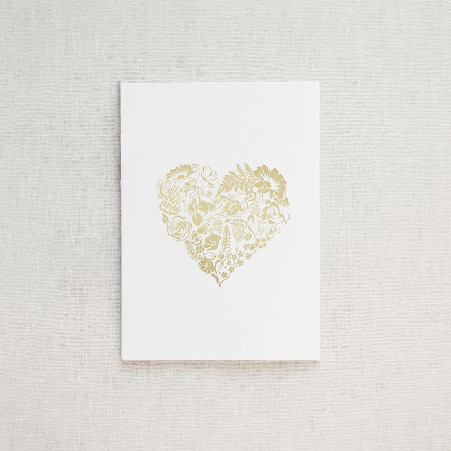 A simple yet elegant card, featuring a heart-shaped floral design rendered in gold foil, centered on a crisp white background.