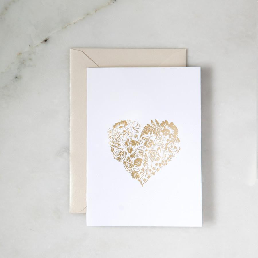 A simple yet elegant card, featuring a heart-shaped floral design rendered in gold foil, centered on a crisp white background.