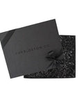 Black box embossed with foxblossom co. filled with black paper shred and tied with black ribbon.