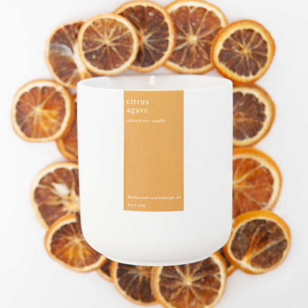 Citrus agave  soy candle in matte white ceramic jar, pictured on dried orange slices.