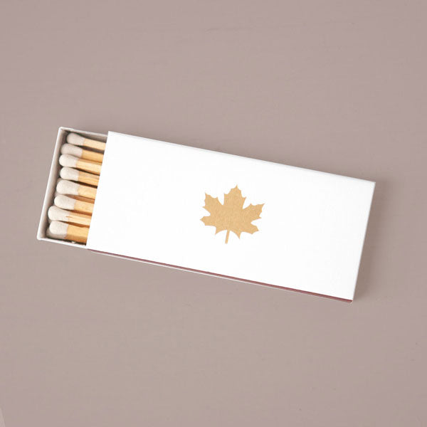 white candle matchbox with maple leaf in gold foil