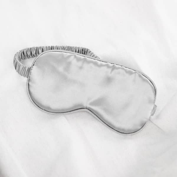 Satin eye mask in silver features on a white background. 