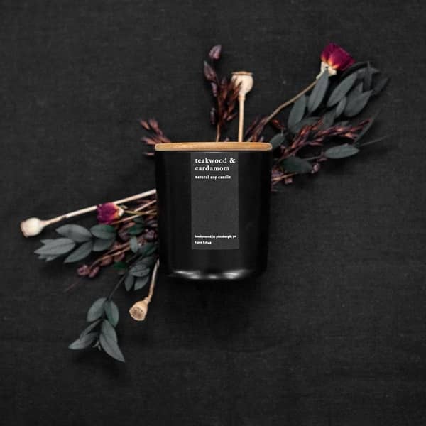 Handpoured teakwood and cardamom natural soy candle in matte black glass jar with bamboo lid. 