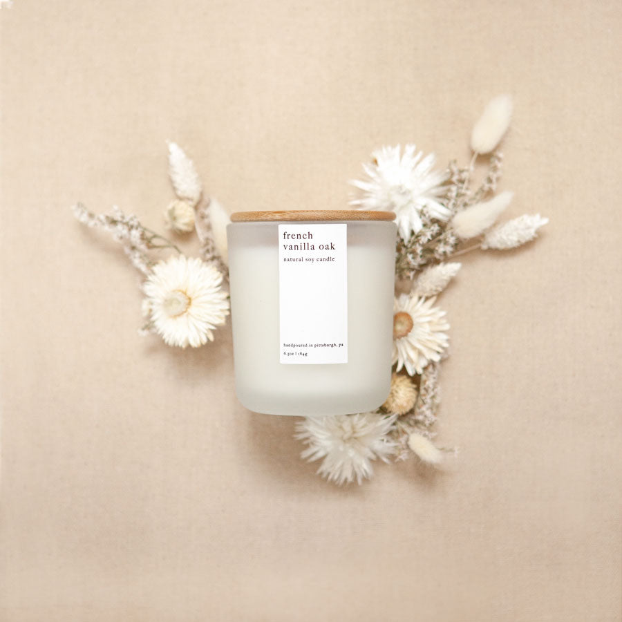 Handpoured french vanilla oak natural soy candle in frosted glass jar with white/black foil label and natural bamboo lid.