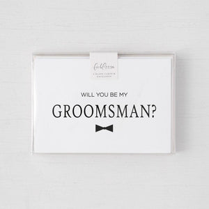 White envelope size card (approx. 3.5" x 5"), reads, "Will you be my groomsman?" in black text, with a bowtie graphic in a clear plastic cover.
