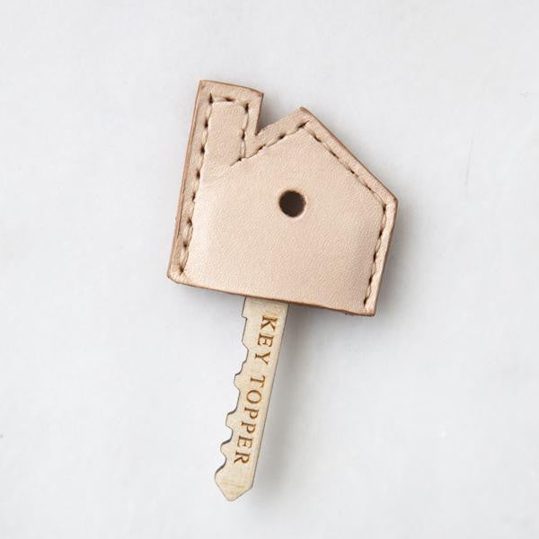 leather house shaped key topper tan in color made of leather shown on wooden key and white background
