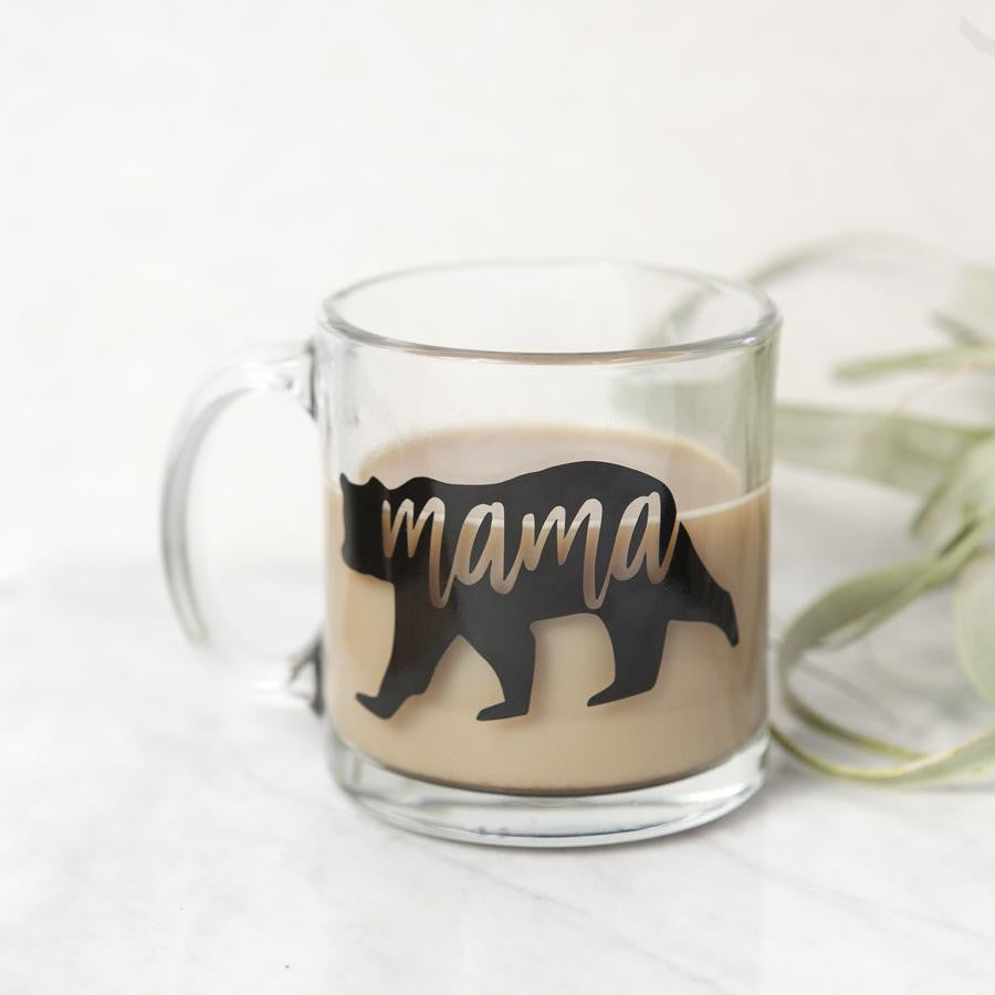 Mama bear mug featured: a transparent mug with a silhouette of a bear in black, cut out from it, on a marble-like background with an air plant next to it. 