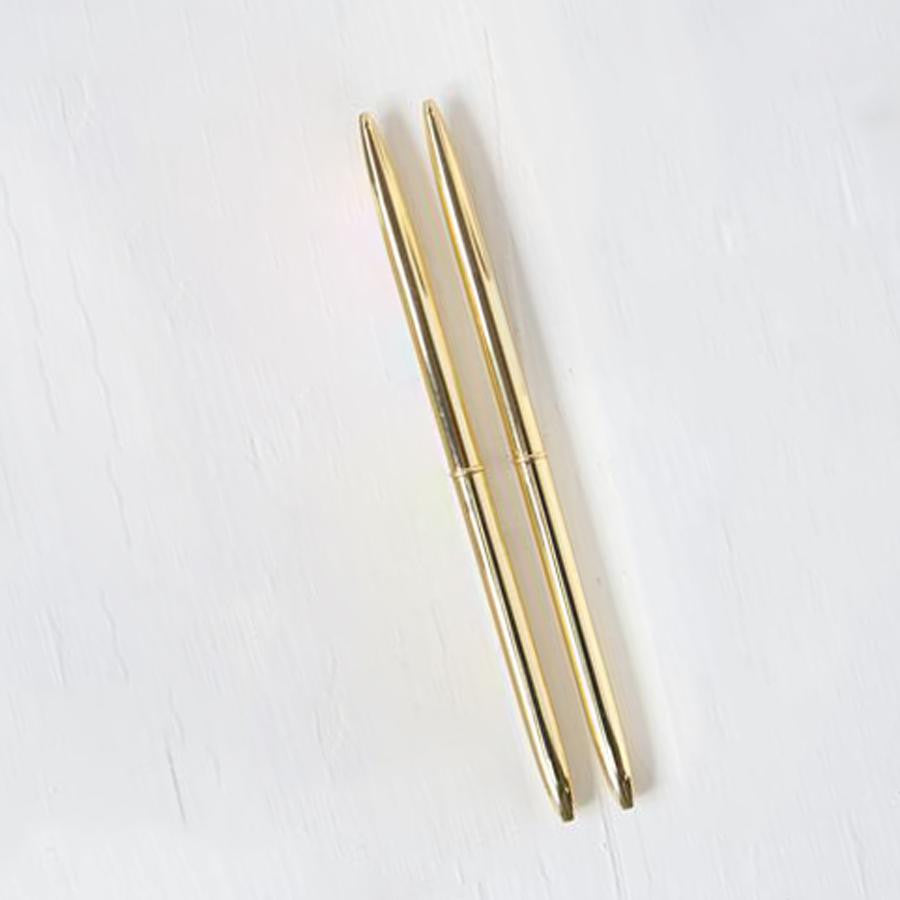 Two minimalist gold pens are featured on a white background.
