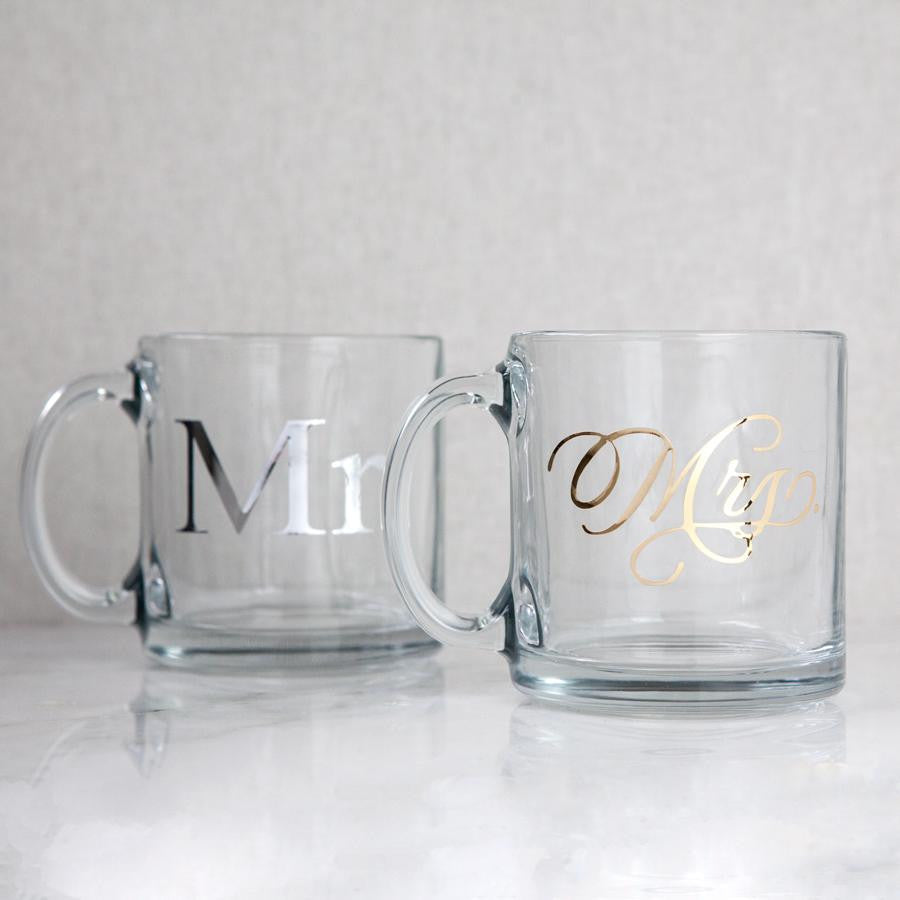 Two clear mugs, featuring 'Mr' in silver lettering and 'Mrs' in gold lettering. On a white background.