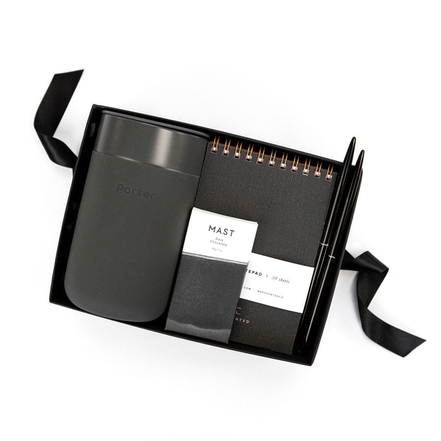 A small black gifting box with a 16oz dark grey Porter mug, a mini dark Mast chocolate bar, a spiral bound dark grey Appointed Pocket Notepad, and two black pens.