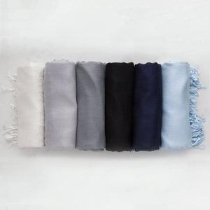 Display of 6 pashminas. White, light grey, ash grey, black, newport navy and light blue.