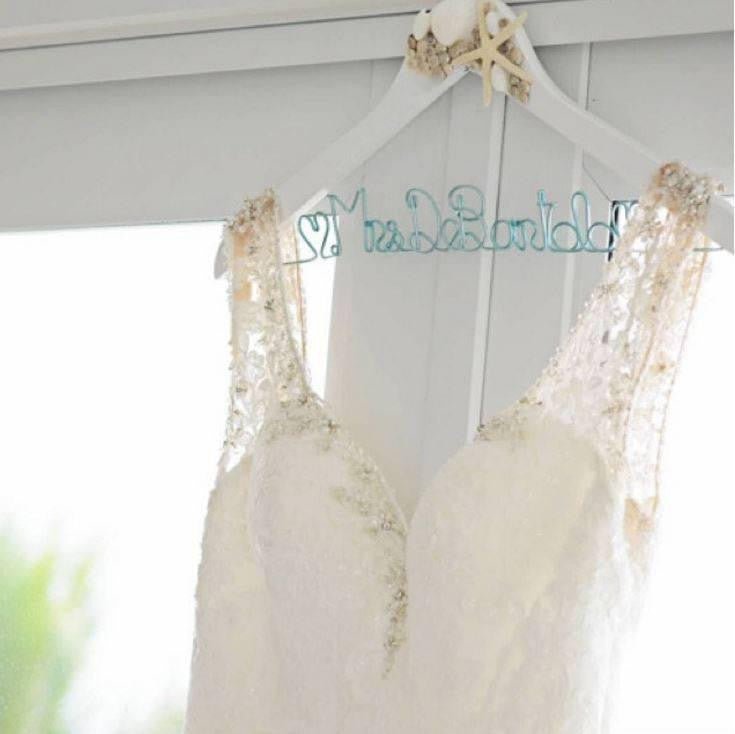 Wedding dress hanging on a white seashell and starfish hanger with ice blue aluminum wire, handcrafted name. " Mrs.DeBartolo" and heart shapes at the beginning and end.