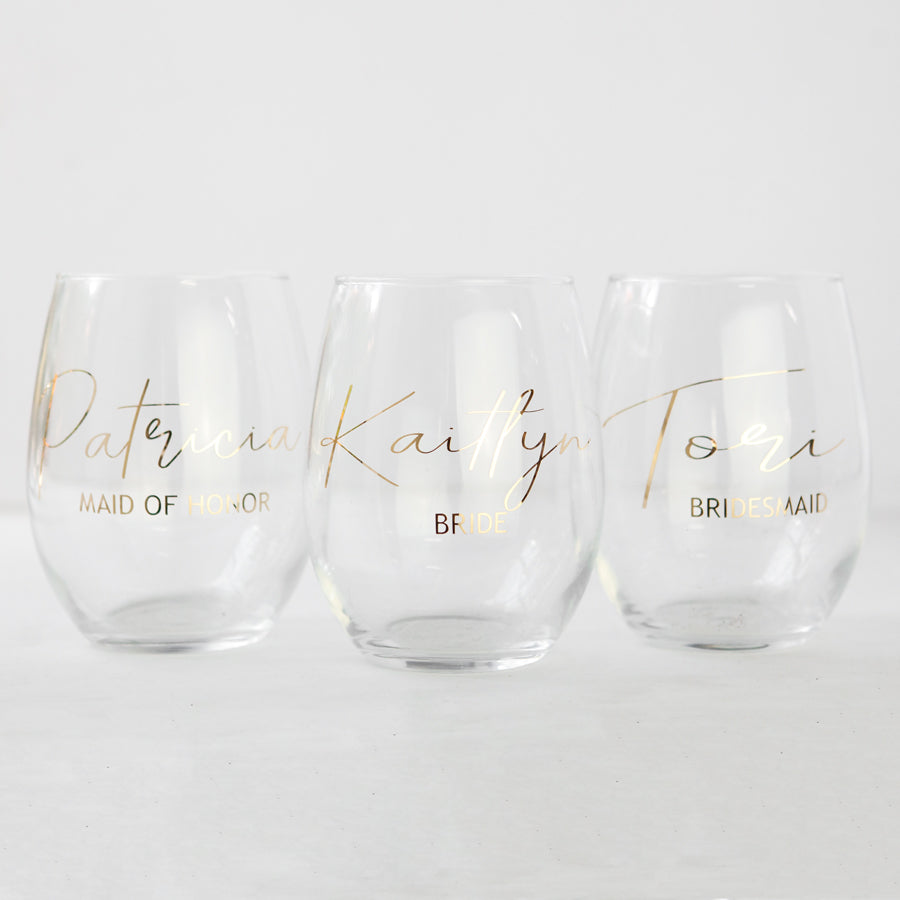 Personalized bridal party wine glasses, three featured with mirrored gold lettering, reading from left to right: Patricia – Maid of Honor, Kaitlyn – Bride, and Tori – Bridesmaid.