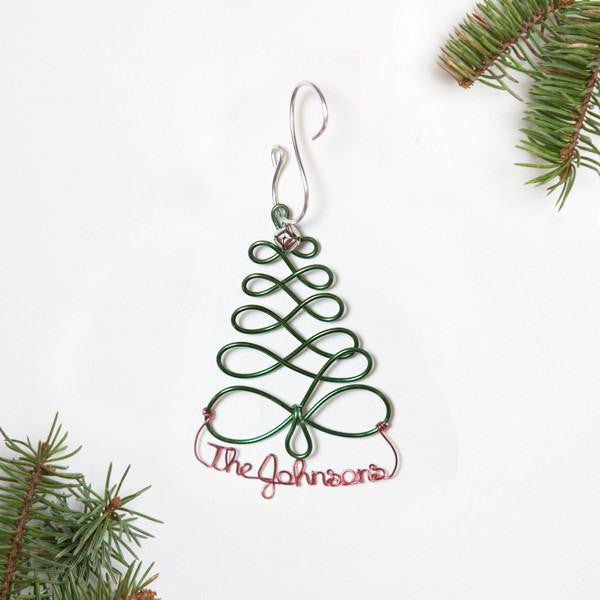 Personalized Christmas Tree Ornament — Christmas tree outline-shaped ornament crafted from green aluminum wire and personalized in red aluminum wire with The Johnsons and decorated with tree branches in each corner on a white background.