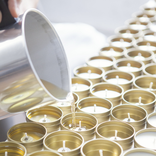 Perzonalized wedding candle favors featured in the picture being poured by a man with a gray tin.