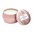 Metallic pink jar with lid removed and propped against the container showing a white candle inside.  