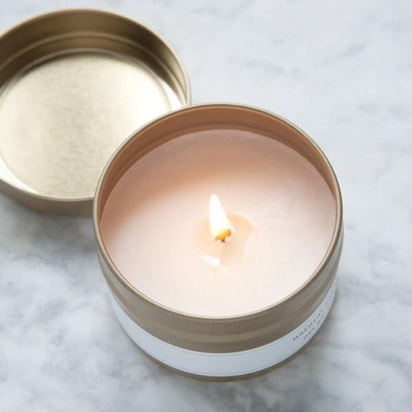 Sliced apple cider candle shown open and lit against a marble, white, and grey background. 