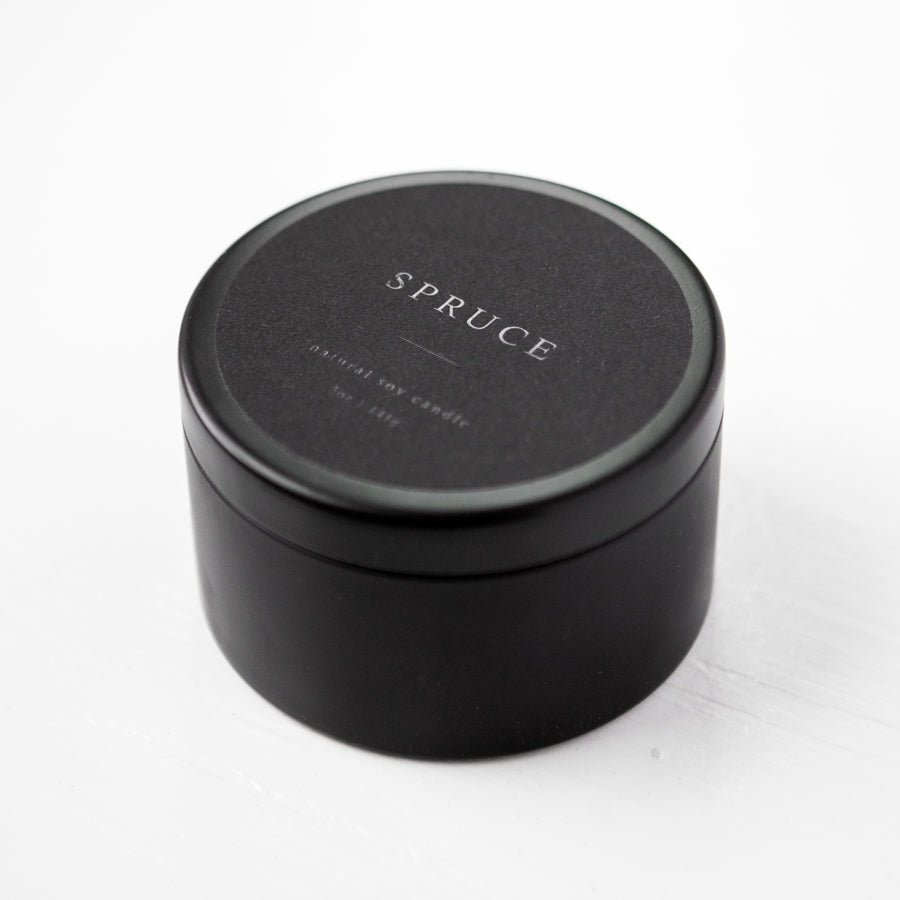 Spruce natural soy candle in its black tin container with black label and white lettering featured. 