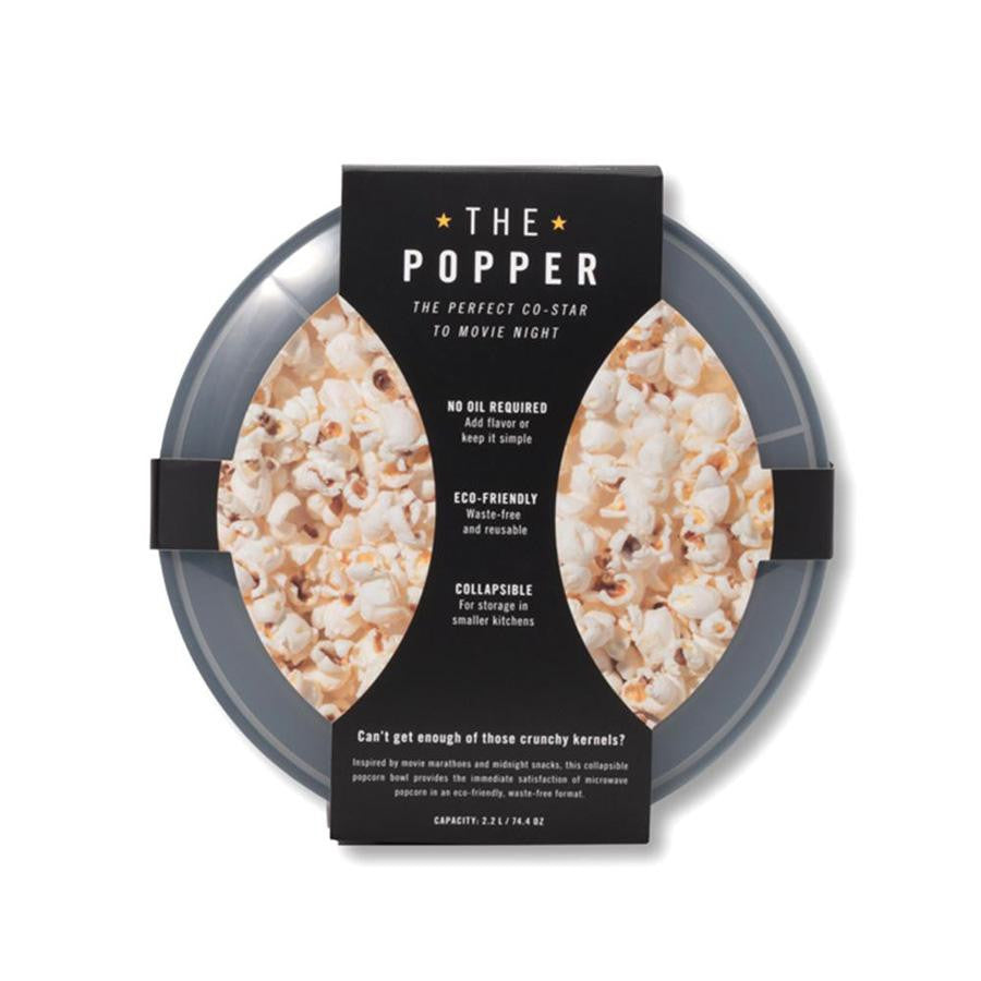 The popper, black collapsed popper viewed from top with lid on and cardboard cover with the information in white lettering.