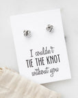 Tie the knot earrings is featured attached to their white earring card that says in black lettering " I couldn't tie the knot without you" on a marble like background and sachet piece in the corner. 
