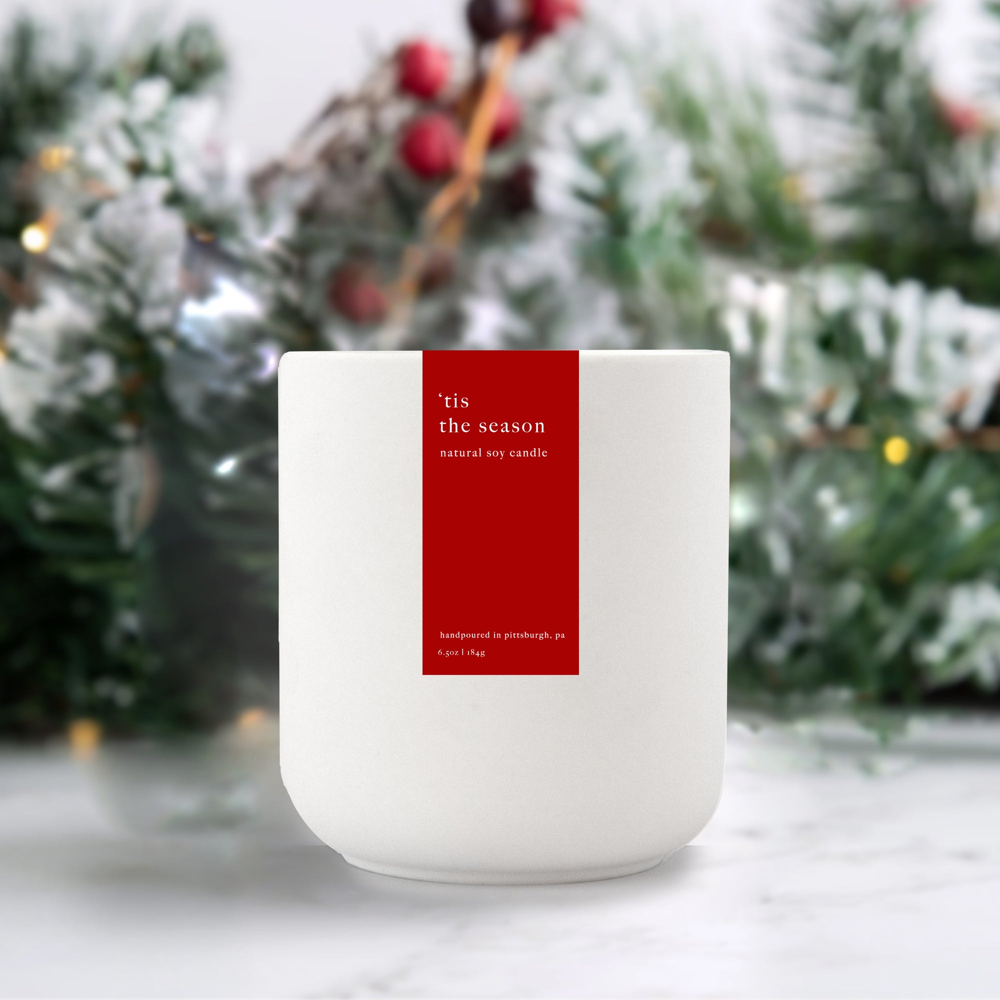 9 oz. 'Tis the Season Cereamic Handpoured candle in a white reuseable ceramic tumbler, red label with white text on one side.