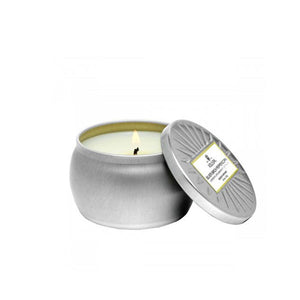 Silver jar with lid removed and propped against the container showing a white, lit candle inside.