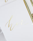 White vow book that reads "Her vows" in gold foil.